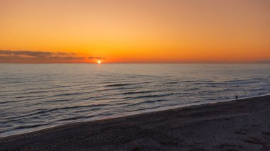 Top view of the sunset. The sun disappears between the waves. Orange and crystal.