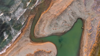 Fantastic landscape taken from the drone. Mignone river, fantastic game of colored curves. Civitavecchia, Italy. Clear sea and blue sky. Waves and sand.