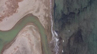 Fantastic landscape taken from the drone. Cloudy skies and wet day. Fiume Mignone, fantastic game of colored curves. Civitavecchia, Italy. Waves and sand.