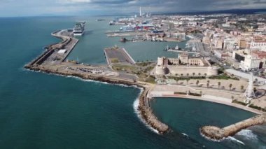 Panoramic view of the city of Civitavecchia with the adjoining tourist port and Forte Michelangelo. Emerald sea and view with tropical palm trees. Ferris wheel and cloudy sky.
