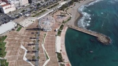 Panoramic view of the city of Civitavecchia with the adjoining tourist port and Forte Michelangelo. Emerald sea and view with tropical palm trees. Ferris wheel and cloudy sky.