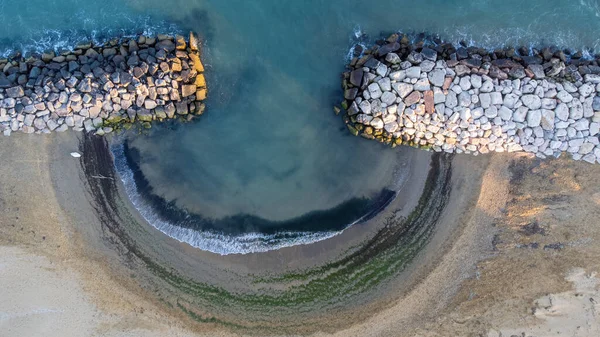 Aerial shot of the beach of Bibione, Venice. Crystal clear water and white rocks. Golden beach and circular shapes. Heaven on earth in Italy, near the Tagliamento river.