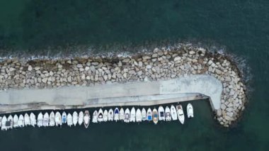 Kayalarla korunan küçük bir limana demirlenmiş teknelerin hava görüntüleri. İtalya