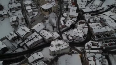Bolzano karlı manzarası ve ortasında kırmızı kilise var. Kentsel bir alanda kar yüklü Alpler