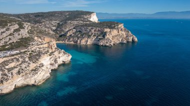 Cagliari 'deki Sella del Diavolo' nun insansız hava aracı görüntüsü. Güneşli bir gün, tekneli berrak bir deniz..