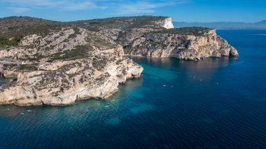 Cagliari 'deki Sella del Diavolo' nun insansız hava aracı görüntüsü. Güneşli bir gün, tekneli berrak bir deniz..