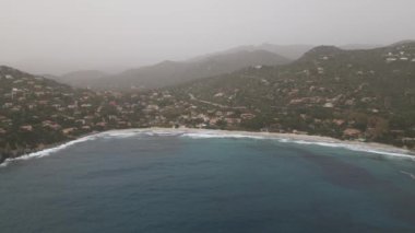 Sardinya 'da kumsalda rüzgarlı bir gün. Suyla dolu açık deniz dalgaları. Bulutlu