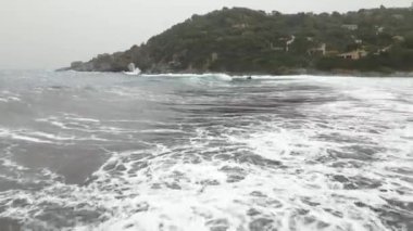 Sardinya 'da kumsalda rüzgarlı bir gün. Suyla dolu açık deniz dalgaları. Bulutlu