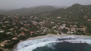 Sardinya 'da kumsalda rüzgarlı bir gün. Suyla dolu açık deniz dalgaları. Bulutlu