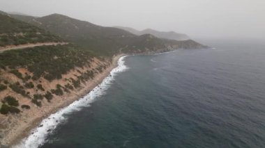 Sardinya 'da kumsalda rüzgarlı bir gün. Suyla dolu açık deniz dalgaları. Bulutlu