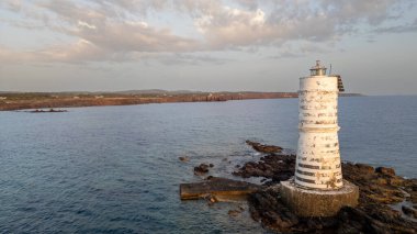 Deniz feneri gün batımında denizle çevrili.