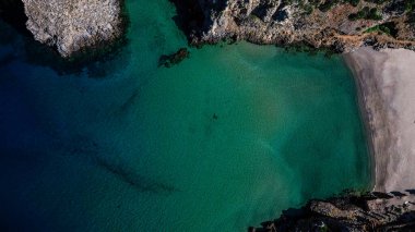 Sardinya 'daki Cala Domestica' da kristal berrak su. İlahi kayaların arasından drone atışı.