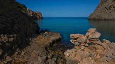Sardinya 'daki Cala Domestica' da kristal berrak su. İlahi kayaların arasından drone atışı.
