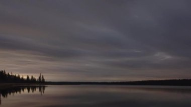 Huysuz gri bulutlar bu zaman atlamasında sakin bir kuzey gölünün üzerinde gece gökyüzünde hareket ederler. Nadiren görülen yıldızlar bulutların arasından görülebilir. Sakin su, kıyı şeridini oluşturan bulutları ve ağaçları mükemmel yansıtır..