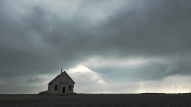 Gri yağmur bulutlarının zaman geçişi ve büyük düz bir tarlada oturan eski tuğla okul binası..