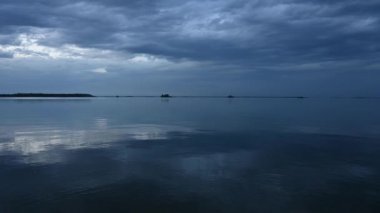 Gecenin ilerleyen saatlerinde, kuzeydeki büyük gölde. Hafif rüzgar, suda ağır bulutları yansıtan küçük dalgalar yaratıyor..