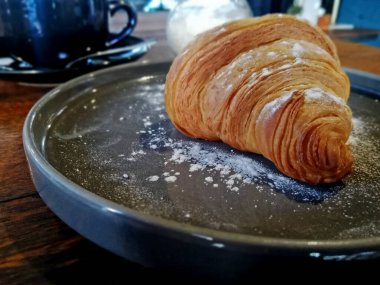 Kahve dükkanındaki seramik tabakta servis edilen kruvasan ekmeği.