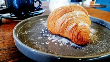 Kahve dükkanındaki seramik tabakta servis edilen kruvasan ekmeği.