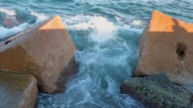 Gün batımında Balear Denizi 'ndeki Dalgakıranlara Karşı Su Sıçramaları' nın Yakın Çekimi. Barcelona, İspanya 'daki Pier On Beach' ten görüntü. Taşın üzerindeki adamın gölgesi. Yüksek kalite 4k görüntü