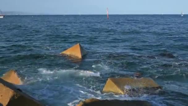 サンセット時のバレアレス海の防波堤に対する水の接近 スペインのバルセロナのビーチの桟橋からの眺め ホライズンで船をセーリング 高品質4K映像 — ストック動画