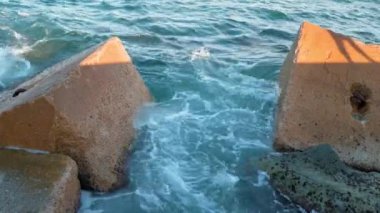 Gün batımında Balear Denizi 'ndeki Dalgakıranlara Karşı Su Sıçramaları' nın Yakın Çekimi. Barcelona, İspanya 'daki Pier On Beach' ten görüntü. Taşın üzerindeki adamın gölgesi. Yüksek kalite 4k görüntü