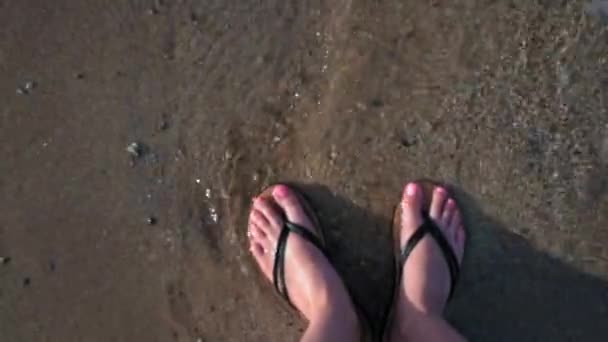 女性の足がフリップフロップでビーチに立ち 水がそれらを洗うので 上からのビデオは焦点から外れています イオニア海の海の波 Moraitika Corfu ギリシャ 高品質4K映像 — ストック動画