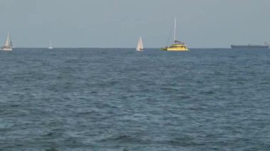 İspanya, Barcelona - 29 Mayıs 2022: Küçük beyaz ve sarı yelkenli ve Güzel Açık Gökyüzü ile Balear Denizi Manzarası. Yüksek kalite 4k görüntü