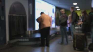 Frame Is Out Of Focus, People At Airport Are Waiting For Their Luggage After Arrival From Conveyor Belt. High quality 4k footage