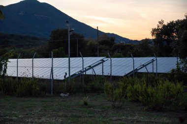 Sunset Karşısındaki Güneş Panelleri Sıraları Dağların Arkaplanı, Korfu, Yunanistan. Dark Key 'de fotoğrafçılık. Yüksek kalite fotoğraf