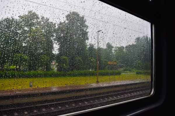 Yazın yağmurlu havalarda tren penceresinden manzarayı seyret. Tren penceresi yağmur damlalarıyla kaplı. Yüksek kalite fotoğraf