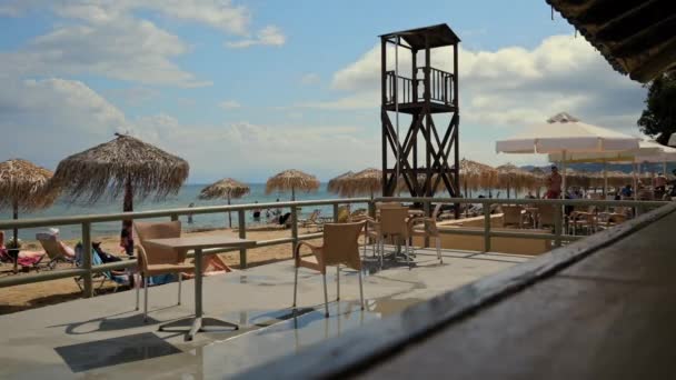 モライティカ ギリシャ 2022 イオニア海の水の近くのサンベッドでタイムラプス人が歩くと日光浴 前景に 雨の後に濡れたビーチカフェのテラス 高品質4K映像 — ストック動画