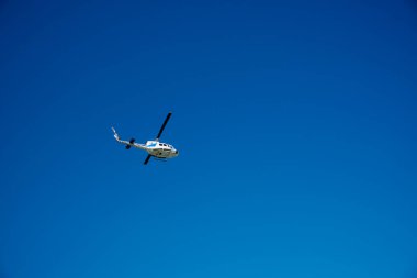 Kerkyra, Yunanistan - 09: 24 2022: Açık mavi gökyüzüne karşı Korfu adasının üzerinde beyaz bir helikopter uçuyor. Yüksek kalite fotoğraf