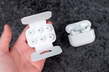 Jurmala, Letonya - 21 09 2023: AirPods profesyoneli için farklı kulak uçları olan kadın el kutusunda, en rahat boyutu seçmek için. Arka planda odak dışı hava kapsülleri var. Yüksek kalite fotoğraf