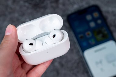 Jurmala, Letonya - 21 09 2023: Kadın elinde kulaklıklı bir çanta var - Airpod Pro 2 nesil. Arka planda akıllı telefon cadıları hava kapsüllerine bağlıdır. Yüksek kalite fotoğraf