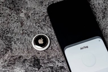Jurmala, Letonya - 21 09 2023: AirTag Apple akıllı telefon cadısıyla etiketli masa başında yatıyor. Eşyalarının izini sürmek için hava etiketi cihazı. Yüksek kalite fotoğraf