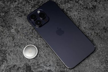 Jurmala, Letonya - 21 09 2023: gümüş AirTag Apple ve iphone masasında. Eşyalarınızı ve paranızı takip etmek için Air Tag cihazı. Yüksek kalite fotoğraf