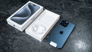 Jurmala, Letonya - 30 11 2023: gri masada mavi Titanyum renkli yeni akıllı telefon iPhone 15 Pro Max 'in kutusunu açmak. Yüksek kalite fotoğraf