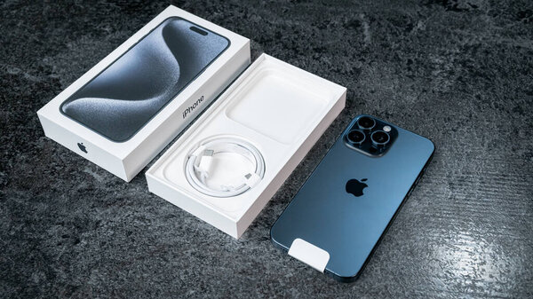 Jurmala, Latvia - 30 11 2023: unboxing of new smarphone apple iPhone 15 Pro Max in Blue Titanium color on grey table. High quality photo