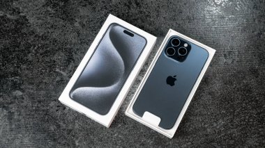 Jurmala, Letonya - 30 11 2023: Kutu ve yeni akıllı telefon iPhone iPhone 15 Pro Max in Blue Titanium rengi gri masa. Yüksek kalite fotoğraf