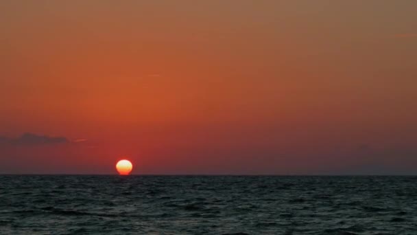 太阳正落在海面上 在水面上投射出温暖的光芒 天空中夹杂着橙色和粉色的色调 营造出宁静祥和的氛围 平静的海水反映了天空的颜色 — 图库视频影像