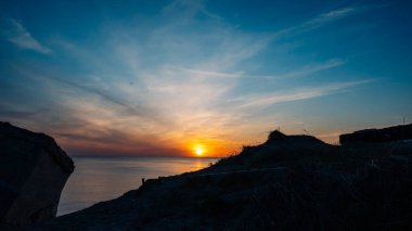 Gökyüzü mavi ve güneş batıyor.