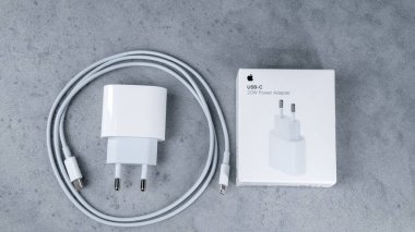 Jurmala, Letonya 22.06.2024: Apple beyaz şarj aleti ve kablolu televizyonu yan yana. Sahne elektronik aygıt, kablo, veri transfer kablosu ve elektronik aksesuar gibi anahtar kelimeleri içerir.