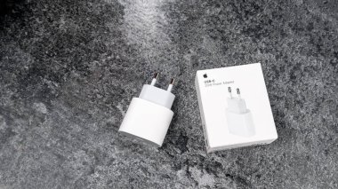 Jurmala, Latvia 22.06.2024: White box from Apples original 20W charging adapter on grey table. High quality photo clipart