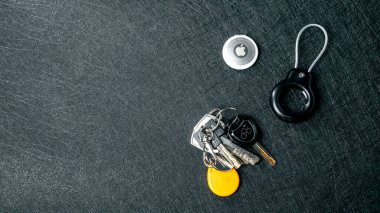 Jurmala, Letonya - 25 06 2024: Bir grup anahtar ve bir anahtarlık Apple Airtag ile koyu renkli düz bir yüzeye yerleştirildi. Yüksek kalite fotoğraf