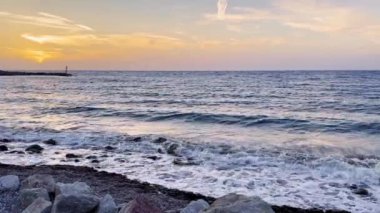 Huzurlu okyanus dalgaları üzerine serinlemek ve rahatlamak için mükemmel bir plajda canlı bir günbatımının tadını çıkar..