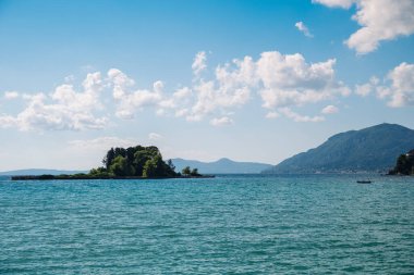 Küçük bir ada büyük bir su kütlesiyle çevrilidir. Gökyüzü açık ve mavidir, birkaç bulut etrafa saçılmıştır. Sahne, ada gibi huzurlu ve huzurlu.