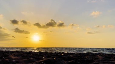 Uçurtmacılar suda süzülürken güzel bir günbatımı okyanusun üzerinde altın renkler bırakır. Sıcak akşam atmosferi, doğal güzelliklere rahatlama ve huşu katar..