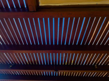 Işık, paralel tahta levhalardan geçerek tavanda desenler oluşturur. Gölgelerin etkileşimi ve aydınlanma oda tasarımına modern bir dokunuş katıyor..