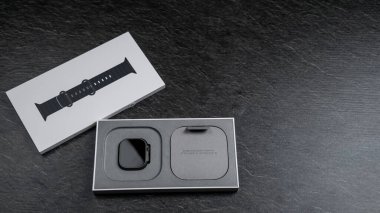 Zarif bir ukala, modern tasarım ve işlevselliği vurgulayarak karanlık bir taş yüzeyde şık ambalajının yanında oturur. Sunum lüks ve yeniliği yansıtıyor.