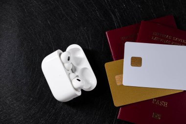 Jurmala, Letonya - 01.05.2025: Apple Kulaklıklar - Airpod Pro 2. Kablosuz kulaklıklar bir yığın seyahat belgesi ve kredi kartının yanında duruyor..